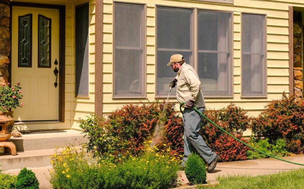 Residential pest control in Greensboro, NC. An exterminator spraying outdoors.